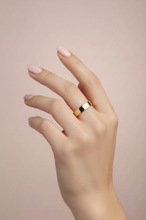 Aliança Ouro Clássica, aro liso em 18K, no dedo, fundo bege, elegante e minimalista